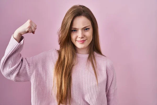 年轻的高加索女人 站在粉红的背景上 强壮的人 显示出臂膀肌肉 自信而自豪的力量 — 图库照片