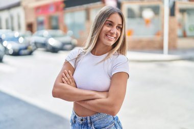 Sokakta kollarını kavuşturmuş genç, güzel İspanyol bir kadın.