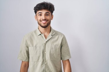 Yüzünde mutlu ve havalı bir gülümsemeyle beyaz arka planda duran sakallı bir Arap. şanslı kişi. 