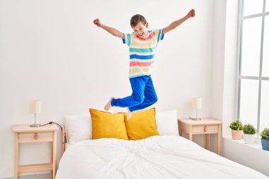 Sarışın çocuk yatakta kendinden emin bir şekilde zıplıyor.