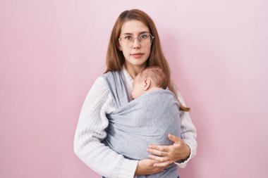 Kafkasyalı genç bir kadın kucağında bebek taşırken askı takınıyor ve aklı başında bir ifade takınıyor. Kendine güveniyor gibi görünüyor. 
