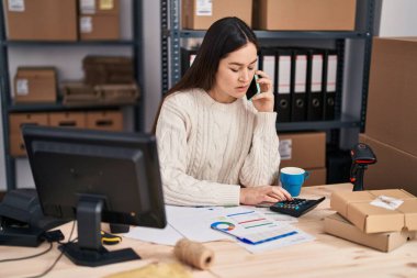 Genç kadın dış ticaret işçisi ofisteki akıllı telefondan konuşuyor.