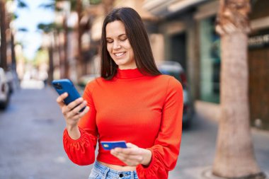 Genç ve güzel İspanyol kadın akıllı telefon ve kredi kartı kullanıyor.
