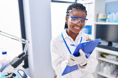 African american woman scientist writing report working at laboratory