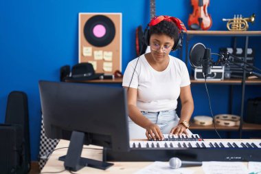African american woman musician playing piano at music studio