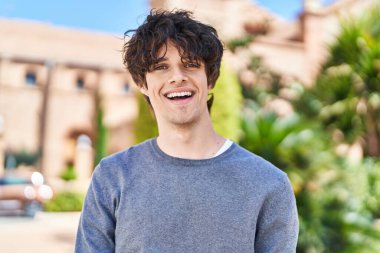 Parkta kendinden emin gülümseyen İspanyol genç adam.