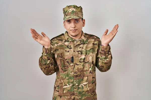 年轻的阿拉伯男子身穿迷彩服 身穿军服 毫无头绪 满脸困惑 举起胳膊和双手 怀疑概念 — 图库照片