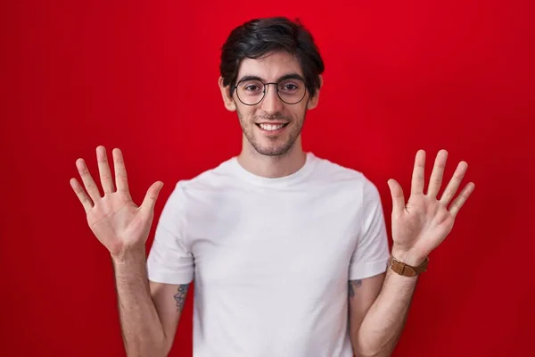 Молодий Іспаномовний Чоловік Стоїть Над Червоним Тлом Показуючи Вказуючи Пальцями — стокове фото