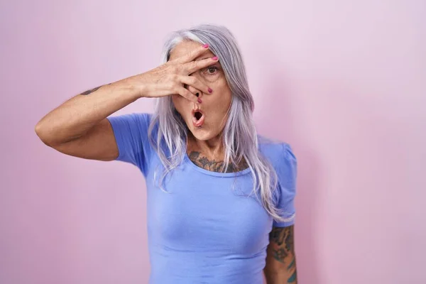 Medelålders Kvinna Med Tatueringar Står Över Rosa Bakgrund Kika Chock — Stockfoto