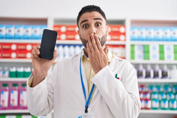 Jovem Hispânico Trabalhando Farmácia Farmácia Farmácia Mostrando Tela Smartphone Cobrindo — Fotografia de Stock