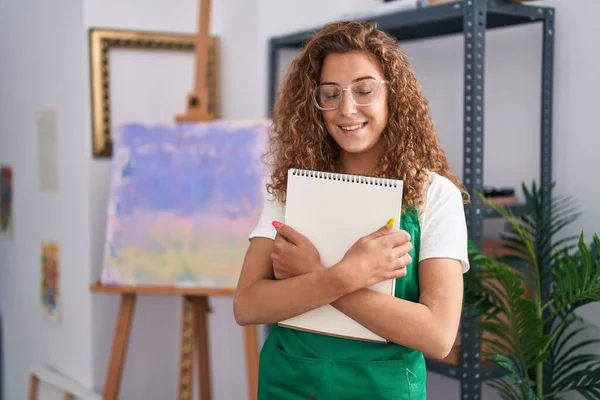 年轻的高加索女人拿着艺术笔记本笑着 脸上带着快乐而沉着的笑容 显示牙齿 — 图库照片