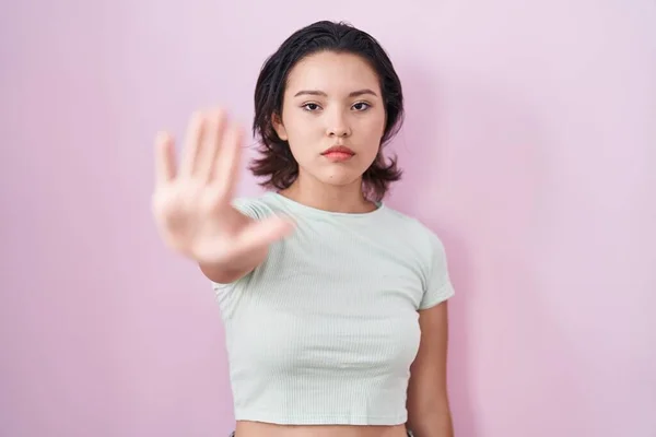 西班牙裔年轻女子站在粉红的背景上 不停地用手掌唱歌 用消极而严肃的手势警告人 — 图库照片
