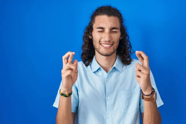 Joven Hombre Hispano Pie Sobre Fondo Azul Gesto Dedo Cruzó —  Fotos de Stock