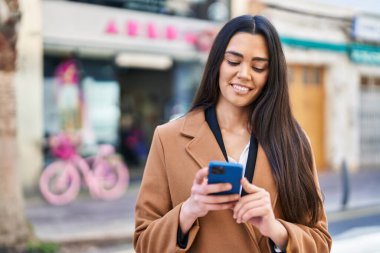 Sokakta akıllı telefon kullanan, kendine güvenen genç İspanyol kadın.