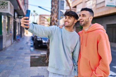 Sokakta akıllı telefondan selfie çeken iki erkek.