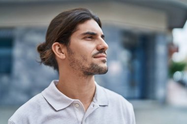 Young hispanic man looking to the side with relaxed expression at street