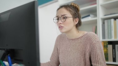 Young beautiful hispanic woman student using computer studying at library university