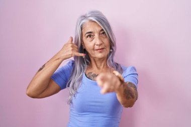 Pembe arka planda duran, gülümseyen, telefonla konuşan ve seni işaret eden orta yaşlı bir kadın. Ara beni.. 