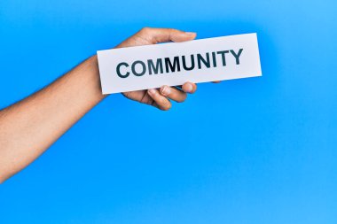 Hand of caucasian man holding paper with community word over isolated white background