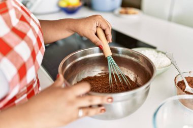 Hispanic brunette woman preparing chocolate cake at the kitchen