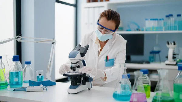 과학자 의료용 마스크를 착용하고 실험실에서 현미경을 사용하는 중년의 지중해 — 스톡 사진