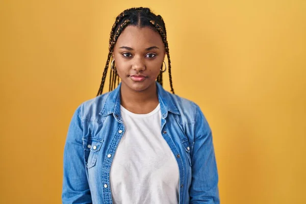 Afroamerikanerin Mit Zöpfen Vor Gelbem Hintergrund Entspannt Mit Ernstem Gesichtsausdruck — Stockfoto