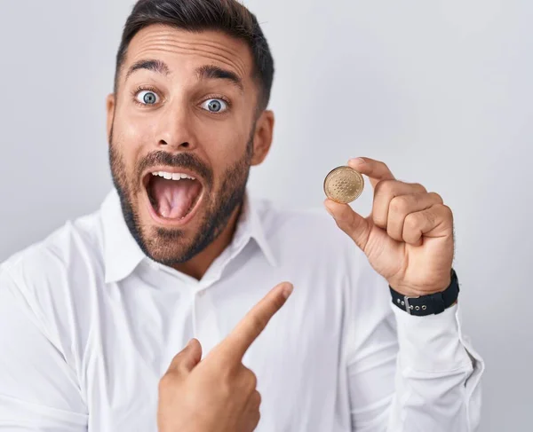 stock image Handsome hispanic man holding cardano cryptocurrency coin smiling happy pointing with hand and finger 