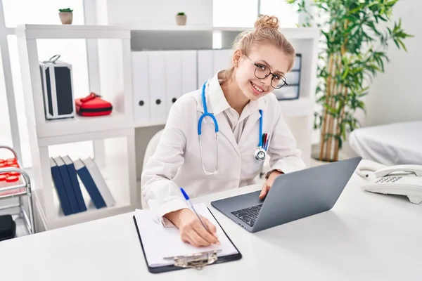 Young Blonde Woman Doctor Using Laptop Writing Medical Report Clinic — Fotografia de Stock