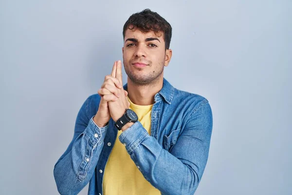 Young Hispanic Man Standing Blue Background Holding Symbolic Gun Hand — Foto de Stock