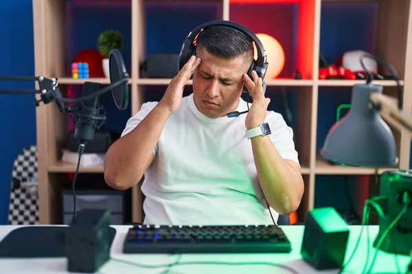 ストレスのために頭の上に手でビデオゲームをプレイ若いヒスパニック系の男 片頭痛 — ストック写真
