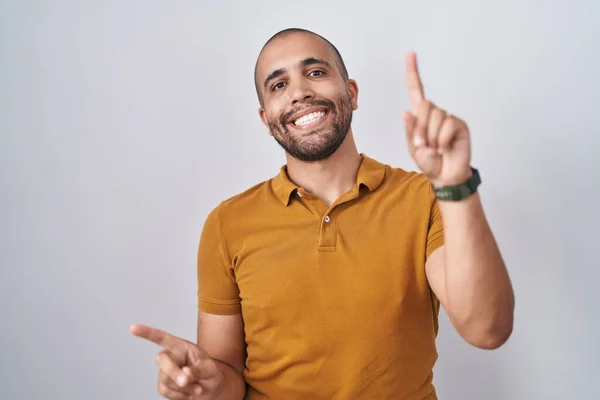 髭を生やしたヒスパニック系の男性は 自信を持ってさまざまな方向に指で指して笑顔の上に立っている 広告のコピースペース — ストック写真