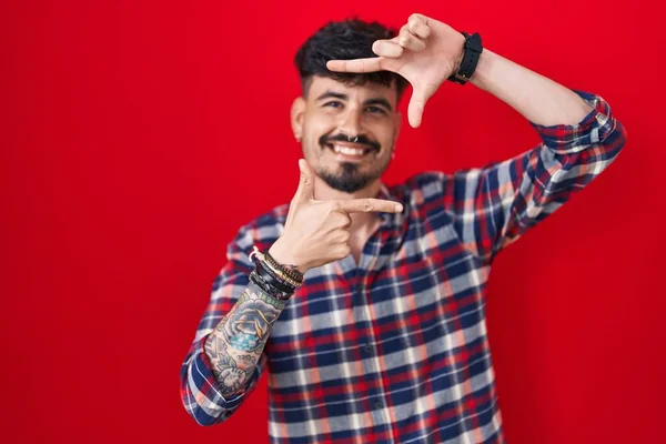 Jovem Hispânico Com Barba Sobre Fundo Vermelho Sorrindo Fazendo Moldura — Fotografia de Stock