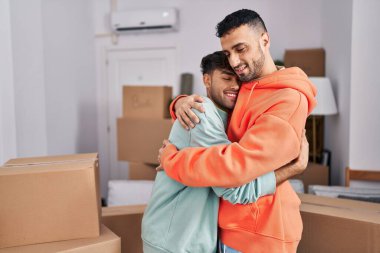 İki erkek yeni evlerinde birbirlerine sarılıyorlar.