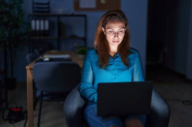 Brunette woman working at the office at night depressed and worry for distress, crying angry and afraid. sad expression. 