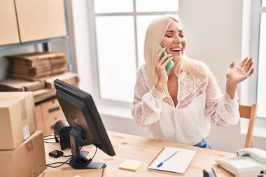 Genç sarışın kadın iş kadını ofisteki akıllı telefondan konuşuyor.