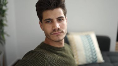 Evdeki rahat ifadesiyle koltukta oturan İspanyol genç adam.