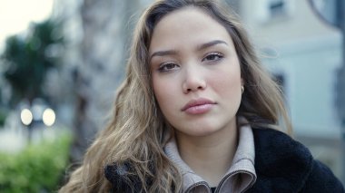 Young beautiful hispanic woman standing with relaxed expression at street