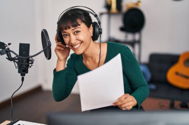 Genç, güzel, İspanyol bir müzisyen müzik stüdyosunda kendine güvenen bir şarkı söylüyor.