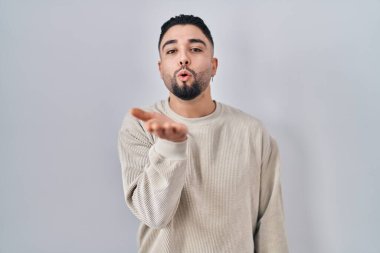 Genç yakışıklı adam izole edilmiş arka planda durup kameraya bakarak havada bir öpücük savuruyor ve sevimli ve seksi oluyor. Aşk ifadesi. 