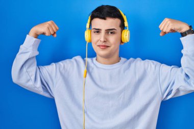 İkili olmayan kişi kulaklık kullanarak müzik dinliyor ve gururla gülümsüyor. fitness konsepti. 