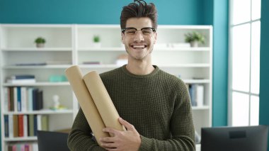 Genç İspanyol öğrenci gülümsüyor kütüphane üniversitesinin planları elinde.