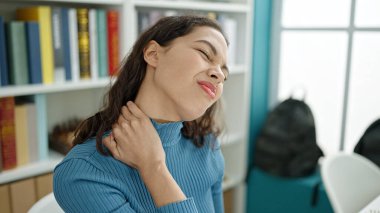 Üniversite sınıfında boynu ağrıyan güzel İspanyol bir kız öğrenci.