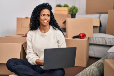 Yeni evinde dizüstü bilgisayar kullanan Afrikalı Amerikalı bir kadın.