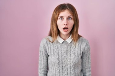 Pembe arka planda duran güzel bir kadın şaşkınlık ve şaşkınlık dolu bir ifade, korku ve heyecan dolu bir yüz.. 
