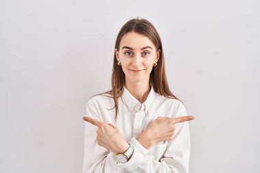 İzole edilmiş arka planda duran genç beyaz kadın her iki tarafı da parmaklarıyla işaret ediyor, farklı yönler farklı. 