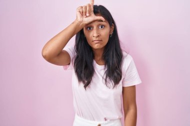 Genç İspanyol kadın pembe arka planda dikiliyor. Alnında parmakları olan insanlarla dalga geçiyor. Ezik hareketler yapıyor, alay ediyor, hakaret ediyor.. 