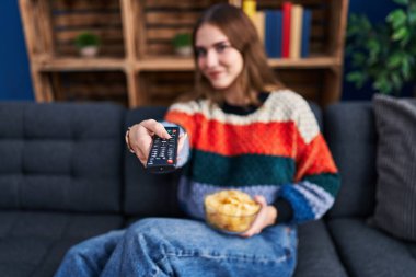 Young woman watching movie sitting on sofa at home