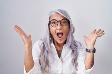 Beyaz arka planda duran gözlüklü orta yaşlı bir kadın çılgın ve başarıyı kollarını kaldırıp heyecanla haykırarak kutluyor. Kazanan konsept 