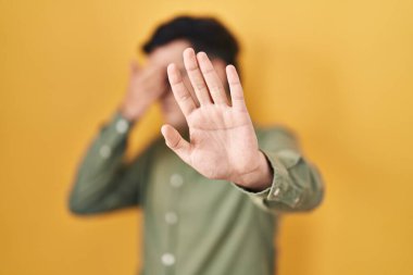 Sarı arka planda duran, elleriyle gözlerini kapayan ve üzgün ve korku ifadesiyle jestleri durduran ikili bir insan değil. utangaç ve olumsuz kavram. 