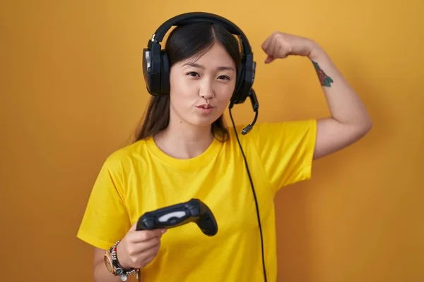 中国年轻女子玩电子游戏手握控制器 强壮的男子展示臂膀肌肉 自信而自豪 — 图库照片